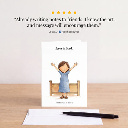The Jesus is Lord card on a table with a white envelope. Review: "Already writing notes to friends. I know the art and message will encourage them." Lola N.