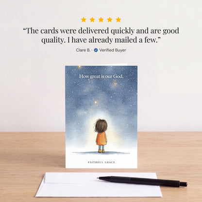 The How great is our God card on a table with a white envelope. Review: "The cards were delivered quickly and are good quality. I have already mailed a few." Clare B.