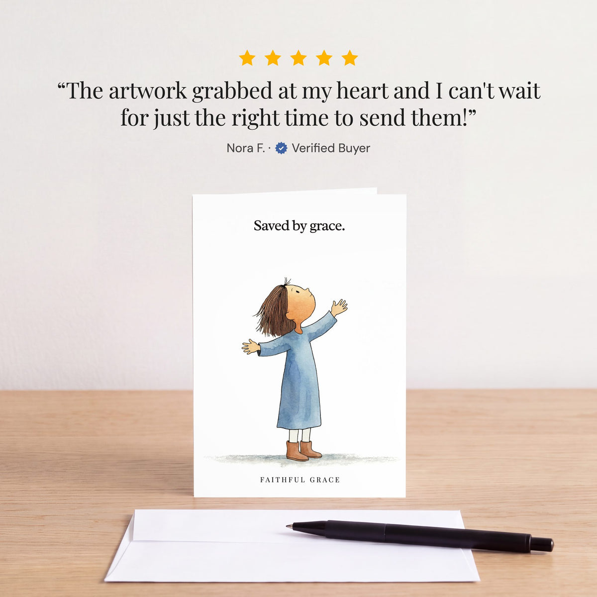 The Saved by grace card on a table with a white envelope. Review: "The artwork grabbed at my heart and I can't wait for just the right time to send them!" Nora F.